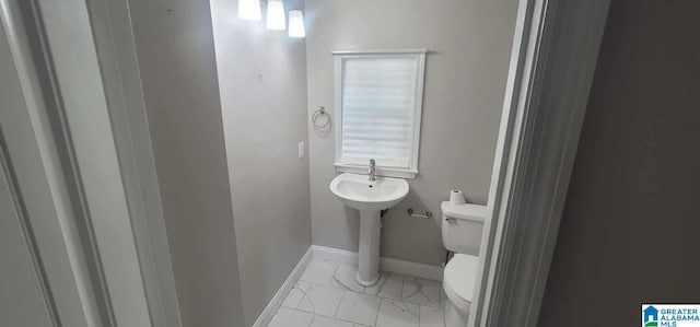 half bathroom with toilet, baseboards, and marble finish floor