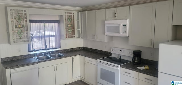 kitchen featuring white appliances, dark countertops, and a sink