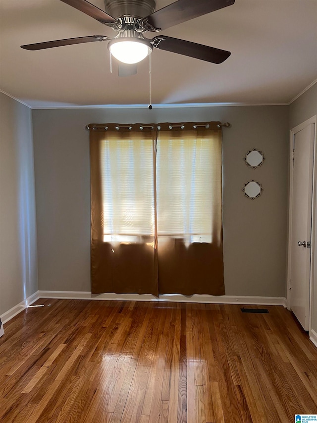 empty room with ceiling fan, hardwood / wood-style flooring, and ornamental molding