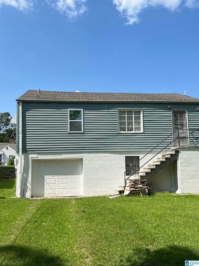 rear view of property with a yard and a garage