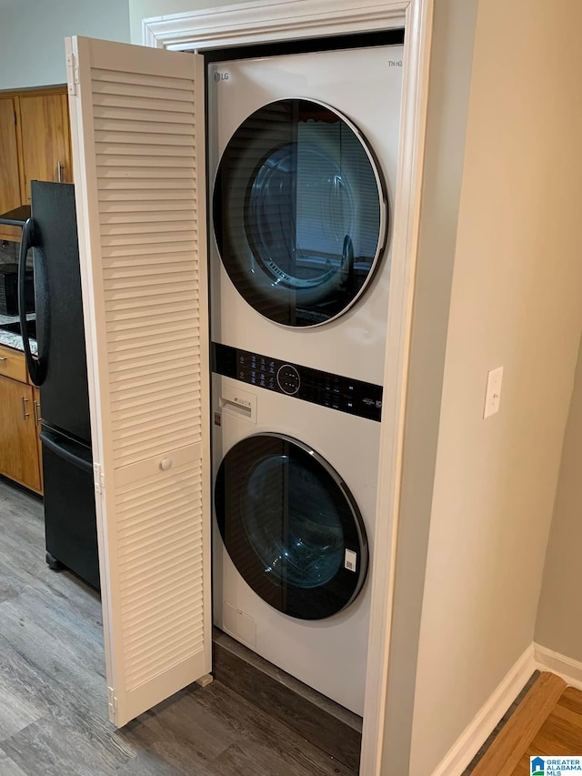 laundry room with dark wood-type flooring and stacked washing maching and dryer