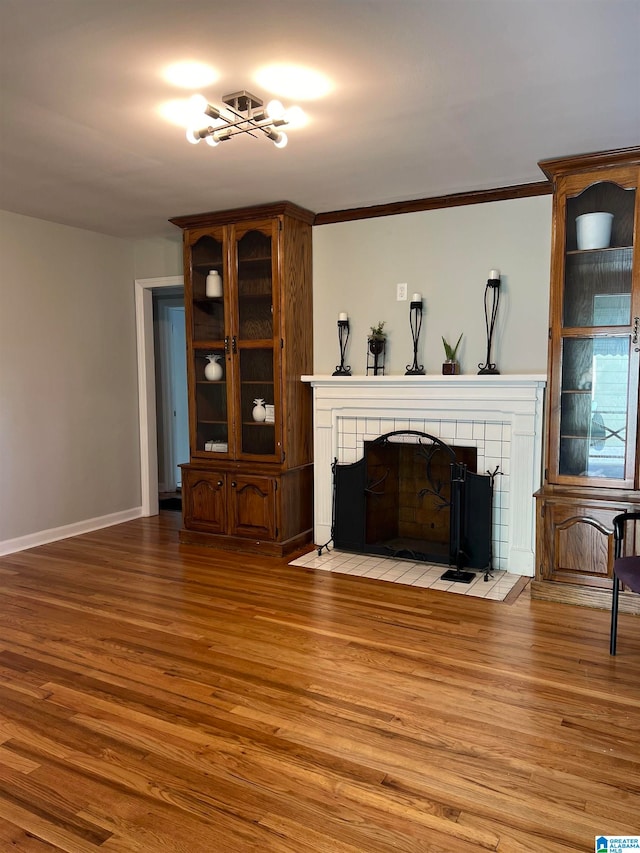 living room featuring ornamental molding, light wood-type flooring, and a tiled fireplace