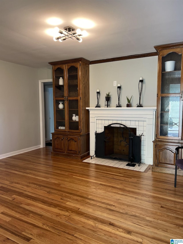 living room featuring a tiled fireplace, hardwood / wood-style flooring, and ornamental molding