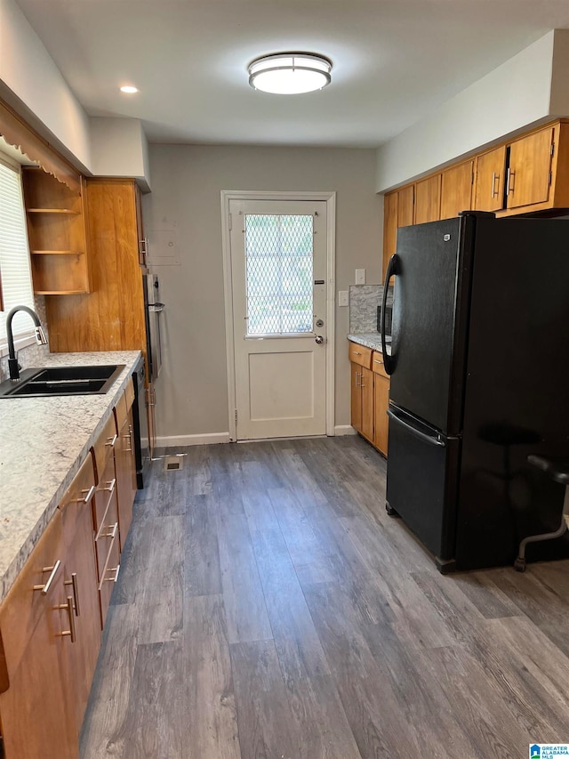 kitchen featuring black fridge, dark hardwood / wood-style floors, sink, and a healthy amount of sunlight