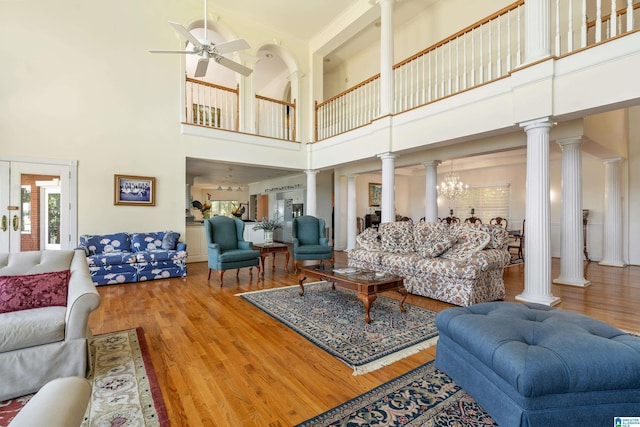 living room featuring ornate columns, hardwood / wood-style floors, and ceiling fan with notable chandelier