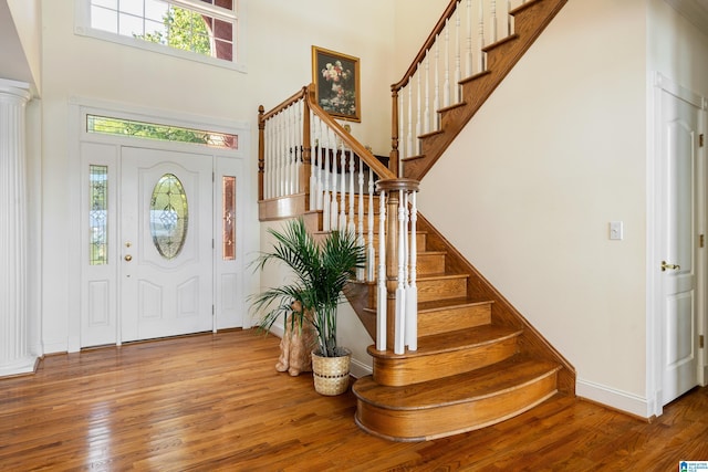 entrance foyer featuring hardwood / wood-style flooring, decorative columns, and a high ceiling