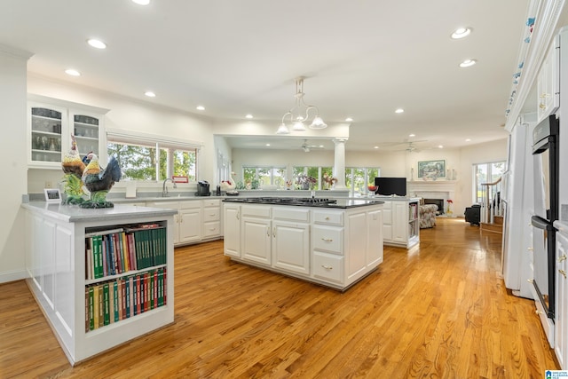 kitchen with sink, decorative light fixtures, a center island, light hardwood / wood-style flooring, and white cabinets