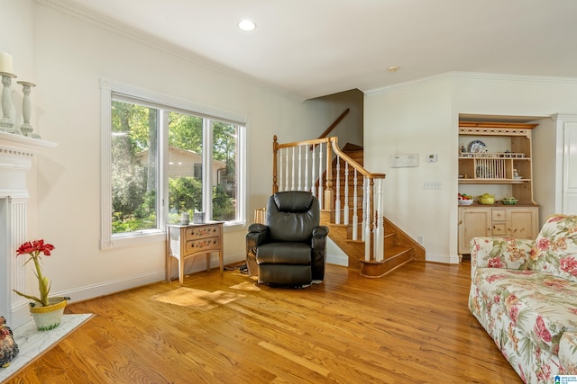 living area with crown molding and light hardwood / wood-style flooring