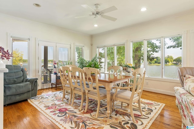 dining space featuring a water view, ceiling fan, crown molding, and light hardwood / wood-style flooring