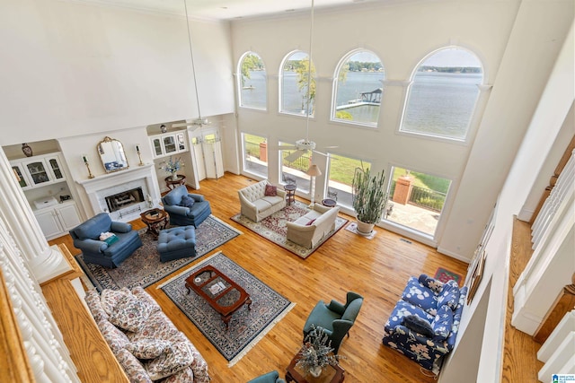 living room featuring hardwood / wood-style flooring, a water view, a high ceiling, and ceiling fan