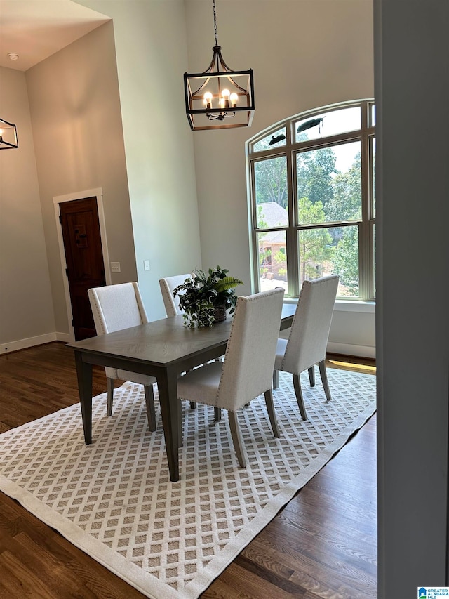 dining space with dark wood-type flooring and an inviting chandelier