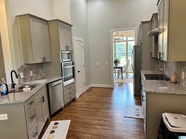 kitchen with sink, gray cabinets, light stone countertops, appliances with stainless steel finishes, and dark hardwood / wood-style flooring