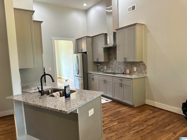 kitchen featuring kitchen peninsula, stainless steel fridge, sink, and black electric stovetop