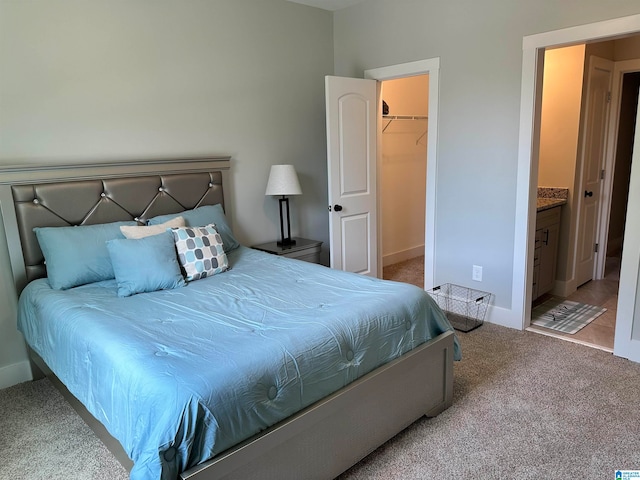 carpeted bedroom with connected bathroom, a walk in closet, and a closet