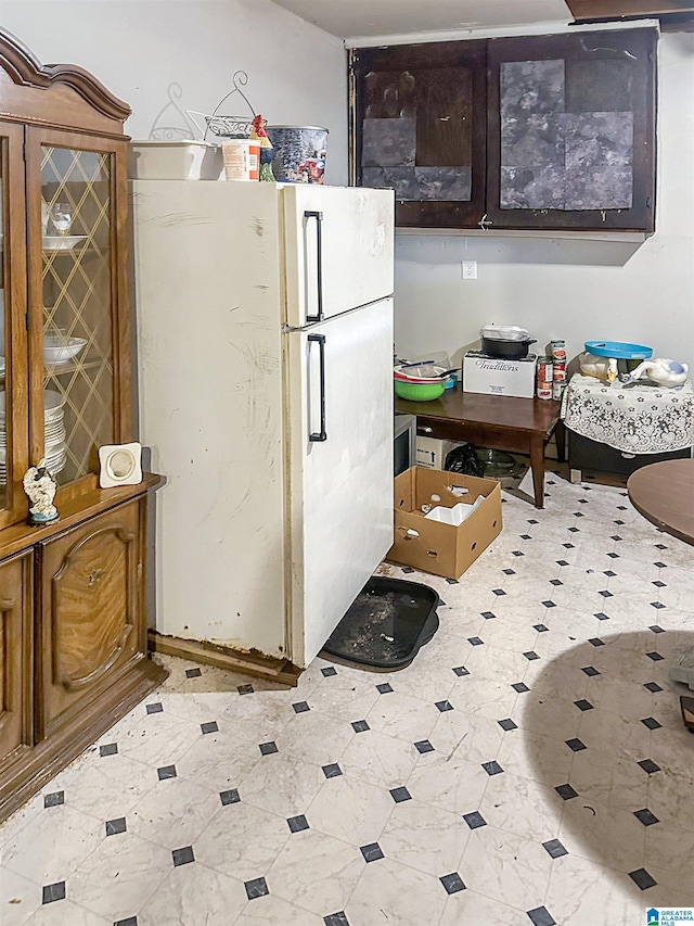 kitchen featuring dark brown cabinetry, glass insert cabinets, and freestanding refrigerator