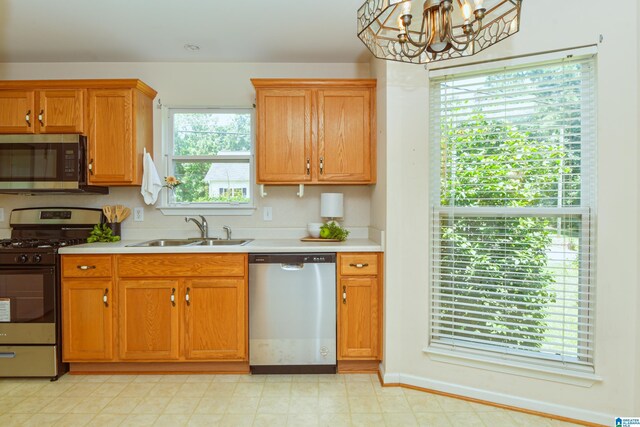 kitchen with light tile patterned flooring, appliances with stainless steel finishes, sink, and an inviting chandelier