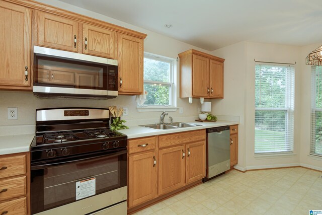 kitchen with appliances with stainless steel finishes, plenty of natural light, light tile patterned floors, and sink