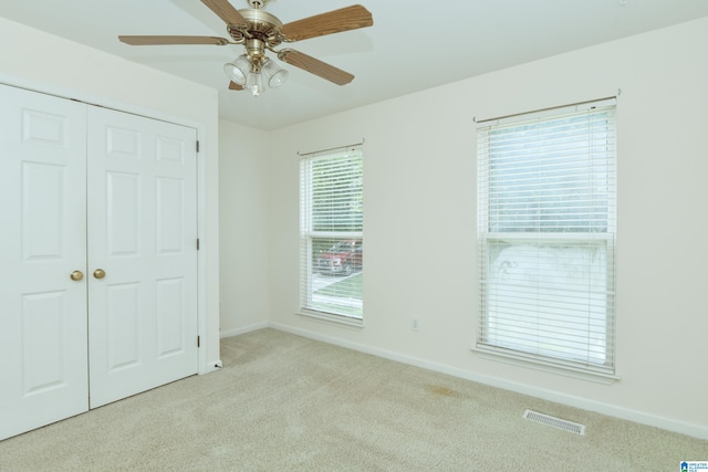 unfurnished bedroom with ceiling fan, light carpet, and a closet