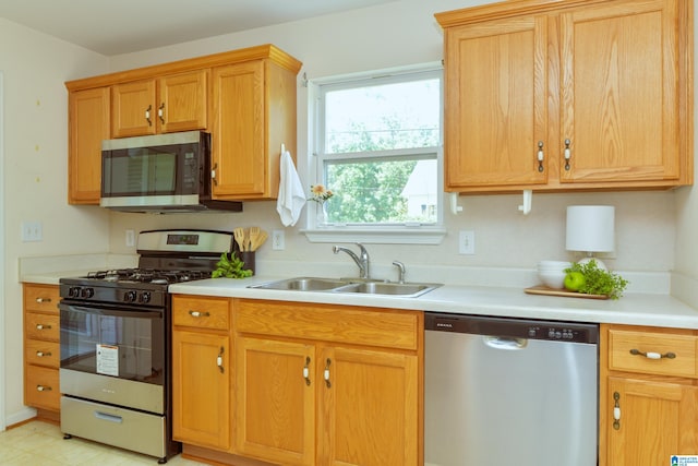 kitchen with appliances with stainless steel finishes, light tile patterned floors, and sink