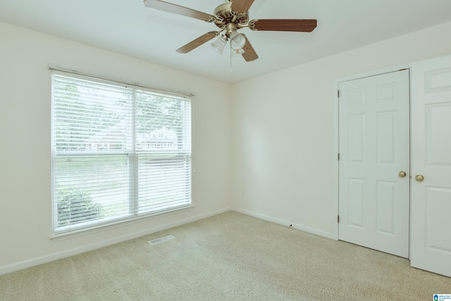 unfurnished bedroom with ceiling fan, light colored carpet, and multiple windows