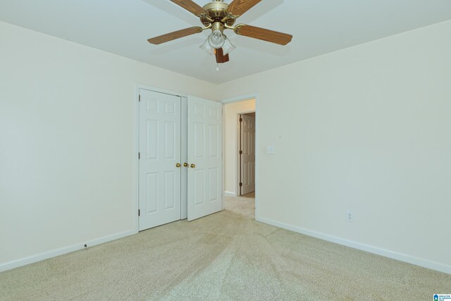 unfurnished bedroom with ceiling fan, light colored carpet, and a closet