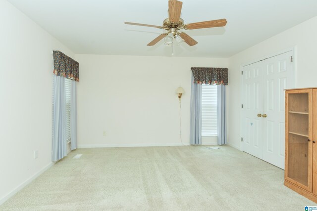 carpeted spare room with ceiling fan and plenty of natural light