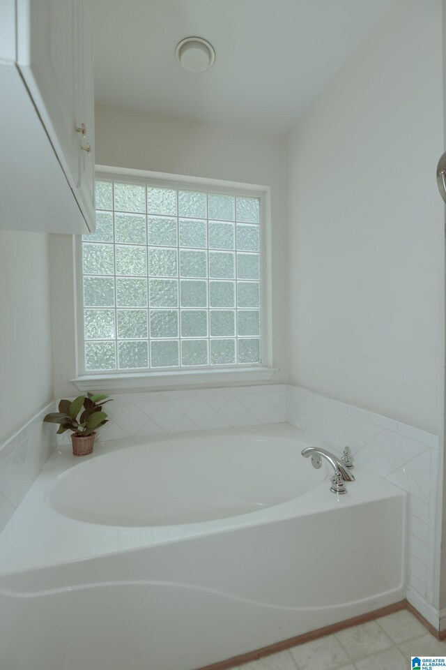 bathroom featuring a washtub, tile patterned flooring, and a healthy amount of sunlight