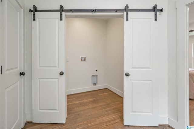 laundry area with hookup for an electric dryer, light wood-type flooring, hookup for a washing machine, and a barn door