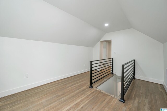 additional living space with hardwood / wood-style flooring and vaulted ceiling