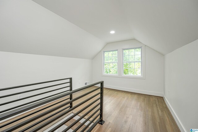 additional living space with light wood-type flooring and lofted ceiling