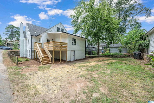 rear view of property featuring a wooden deck and a lawn