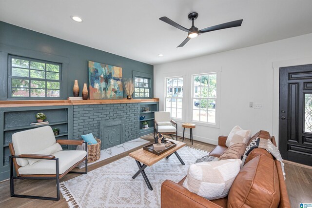 living room with hardwood / wood-style floors, ceiling fan, and a fireplace