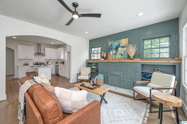 living room with a brick fireplace, ceiling fan, and light hardwood / wood-style floors