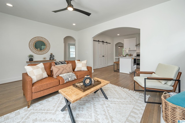 living room featuring ceiling fan, light hardwood / wood-style flooring, and a barn door