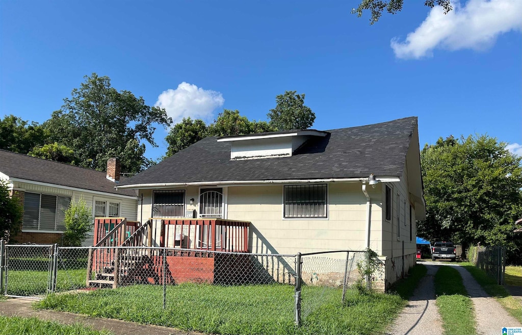 bungalow with a wooden deck and a front lawn