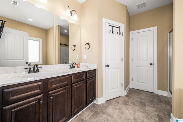 bathroom with double vanity, visible vents, and a sink