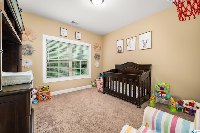 bedroom with a crib, baseboards, visible vents, and carpet floors