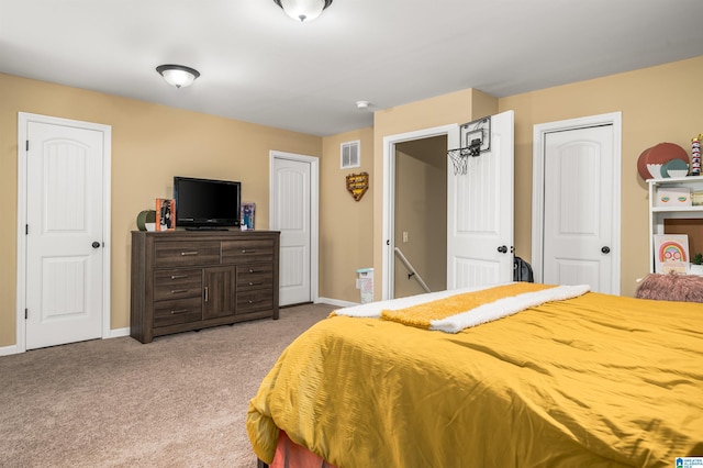 carpeted bedroom featuring visible vents, baseboards, and multiple closets