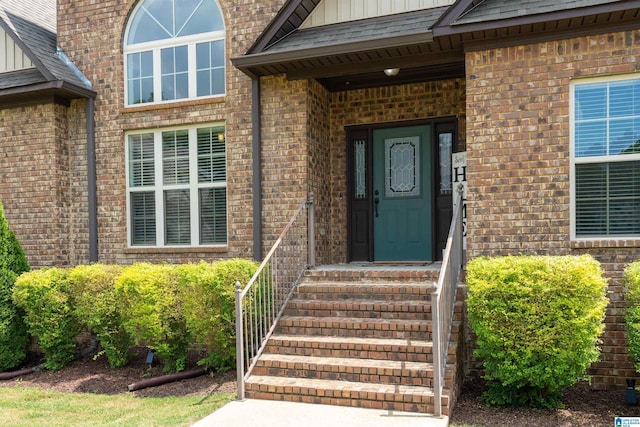 entrance to property with brick siding, board and batten siding, and roof with shingles