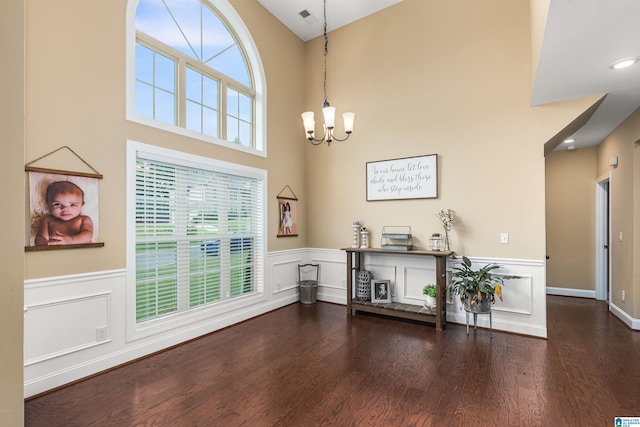 foyer with a chandelier, a wainscoted wall, and wood finished floors