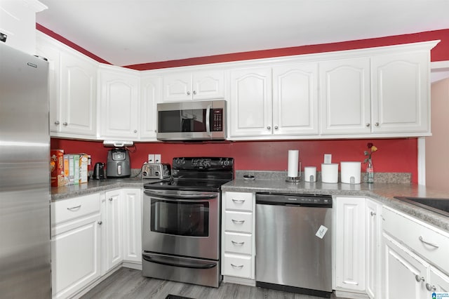 kitchen with appliances with stainless steel finishes, light hardwood / wood-style flooring, and white cabinets