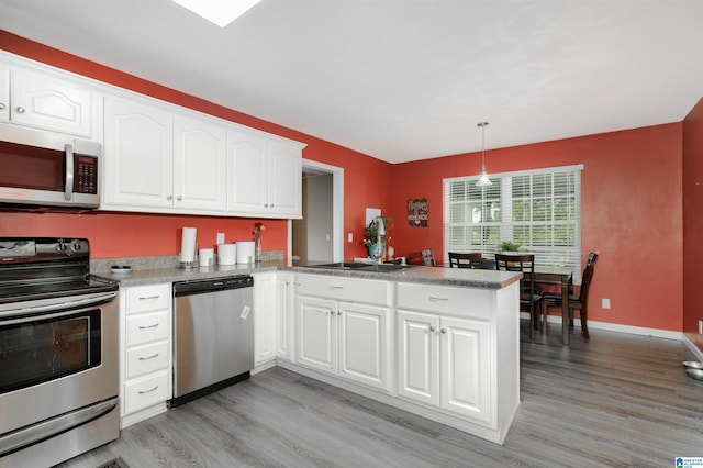 kitchen featuring light hardwood / wood-style floors, appliances with stainless steel finishes, kitchen peninsula, and white cabinets