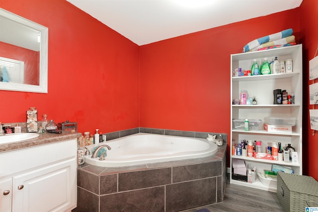 bathroom featuring a relaxing tiled tub, hardwood / wood-style flooring, and vanity