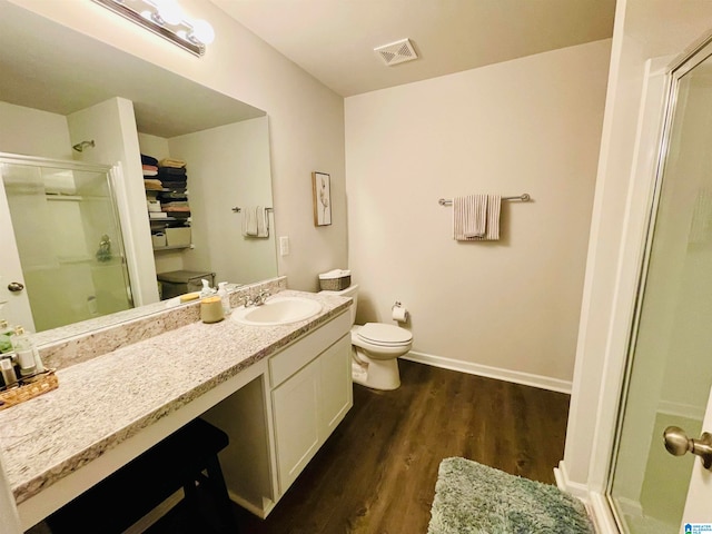 bathroom with hardwood / wood-style flooring, vanity, toilet, and a shower with door