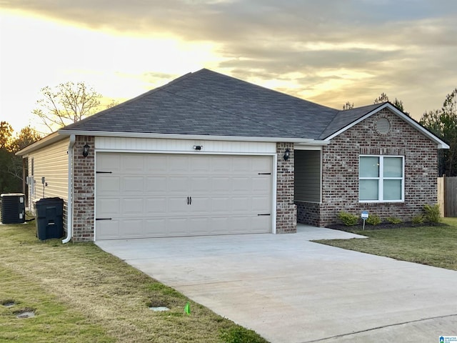 single story home featuring a garage, a yard, and central AC