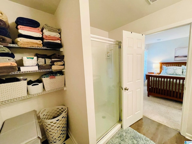 bathroom with wood-type flooring and an enclosed shower