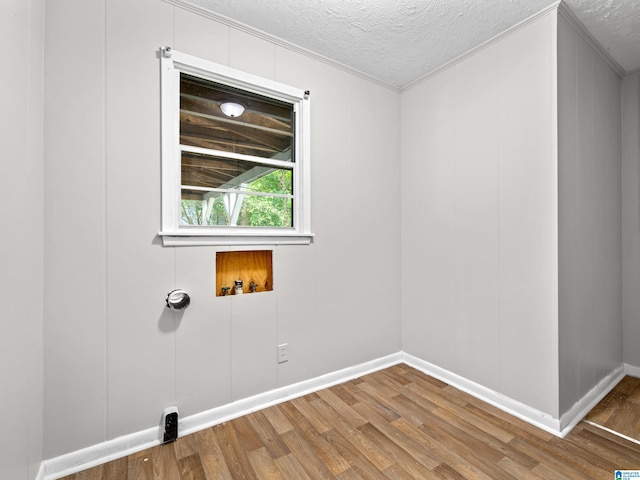 laundry area featuring crown molding, a textured ceiling, hardwood / wood-style flooring, and washer hookup