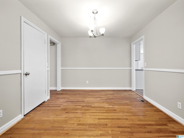 unfurnished room featuring a chandelier and light wood-type flooring