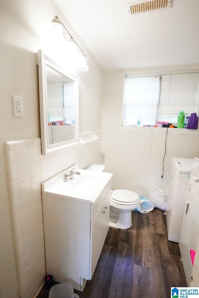 bathroom featuring toilet, wood-type flooring, vanity, and washing machine and clothes dryer