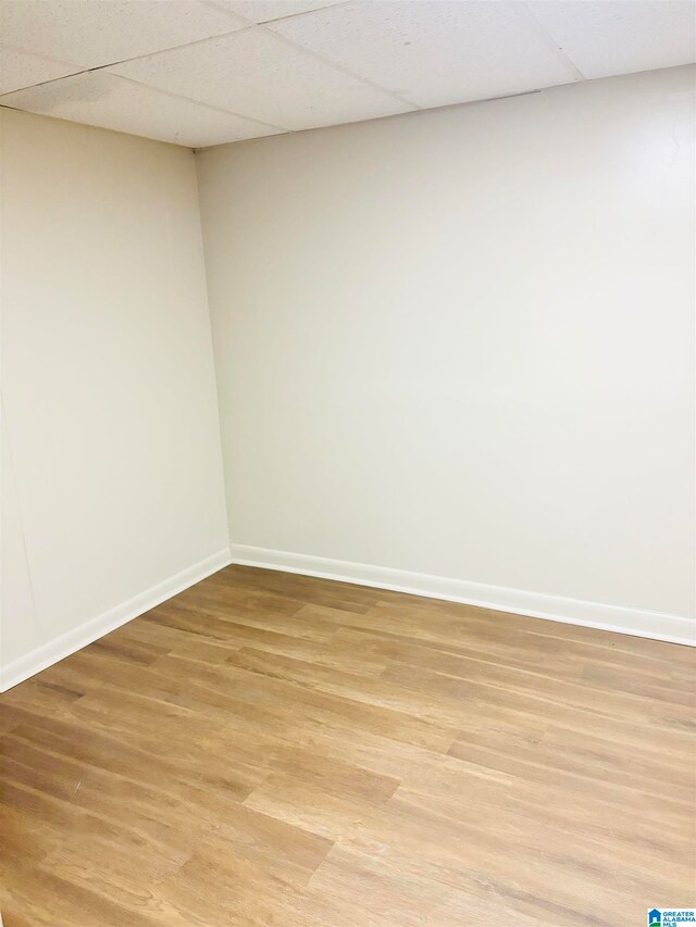 spare room with wood-type flooring and a drop ceiling